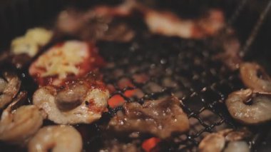 İnsanların ızgara et ve karides pişirmesini yakından izliyoruz. Yakiniku, Japonya 'nın en popüler yemek pişirme tarzlarından biridir..