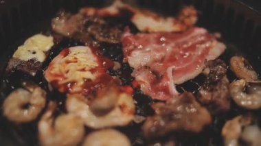 İnsanların ızgara et ve karides pişirmesini yakından izliyoruz. Yakiniku, Japonya 'nın en popüler yemek pişirme tarzlarından biridir..