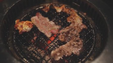 İnsanların ızgara et ve karides pişirmesini yakından izliyoruz. Yakiniku, Japonya 'nın en popüler yemek pişirme tarzlarından biridir..