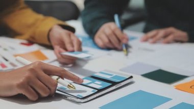 Çalışma alanı boyunca yayılmış prototip çizimleri kullanarak yeni uygulama arayüzü oluşturmada işbirliği yapan tasarım ekibi