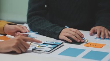 Yeni bir uygulama üzerinde çalışan arayüz tasarımcılarından oluşan bir ekip, prototip modelleri çalışma alanlarına yayılmış durumda.