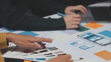 Yeni bir uygulama üzerinde çalışan arayüz tasarımcılarından oluşan bir ekip, prototip modelleri çalışma alanlarına yayılmış durumda.