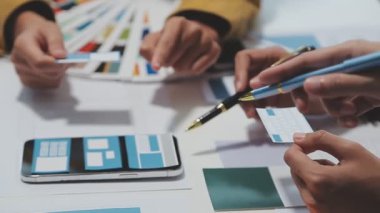 Yeni bir uygulama üzerinde çalışan arayüz tasarımcılarından oluşan bir ekip, prototip modelleri çalışma alanlarına yayılmış durumda.