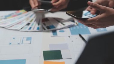 Yeni bir uygulama üzerinde çalışan arayüz tasarımcılarından oluşan bir ekip, prototip modelleri çalışma alanlarına yayılmış durumda.