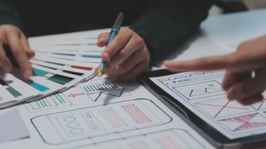 Çalışma alanı boyunca yayılmış prototip çizimleri kullanarak yeni uygulama arayüzü oluşturmada işbirliği yapan bir grup genç şarkıcı