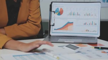 Görsel raporlarla çevrili, çağdaş çalışma alanındaki finansal verileri analiz eden profesyoneller