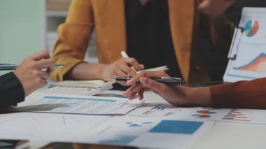Çağdaş çalışma alanında finansal verileri analiz eden bir grup profesyonel iş adamı, görsel raporlarla çevrili
