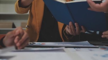 Çağdaş çalışma alanında finansal verileri analiz eden bir grup profesyonel iş adamı, görsel raporlarla çevrili