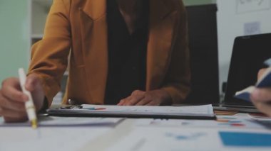 Çağdaş çalışma alanında finansal verileri analiz eden bir grup profesyonel iş adamı, görsel raporlarla çevrili