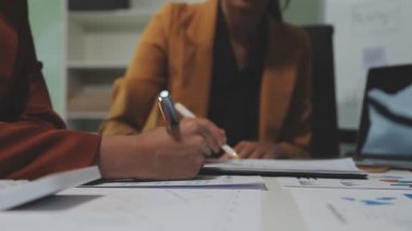Çağdaş çalışma alanında finansal verileri analiz eden bir grup profesyonel iş adamı, görsel raporlarla çevrili