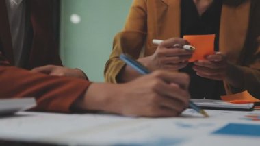 Çağdaş çalışma alanında finansal verileri analiz eden bir grup profesyonel iş adamı, görsel raporlarla çevrili