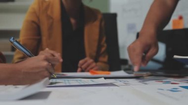 Çağdaş çalışma alanında finansal verileri analiz eden bir grup profesyonel iş adamı, görsel raporlarla çevrili