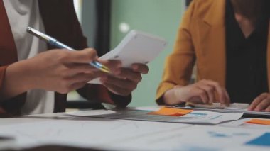Çağdaş çalışma alanında finansal verileri analiz eden bir grup profesyonel iş adamı, görsel raporlarla çevrili