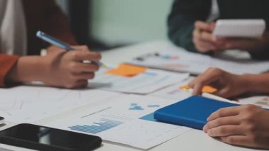 Çağdaş çalışma alanında finansal verileri analiz eden bir grup profesyonel iş adamı, görsel raporlarla çevrili