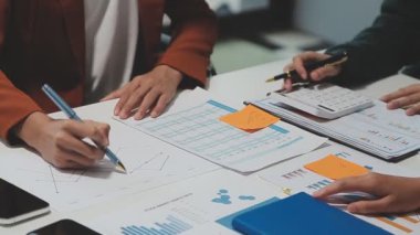 Çağdaş çalışma alanında finansal verileri analiz eden bir grup profesyonel iş adamı, görsel raporlarla çevrili