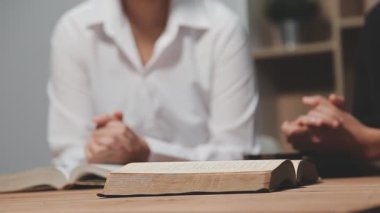 Genç bir kadın Tanrı 'nın İncil' i ile masada dua ediyor.