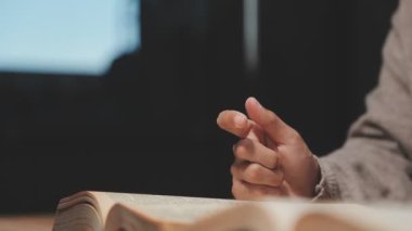 Genç adam ahşap masa üzerinde kitap okuyor, yakın plan.