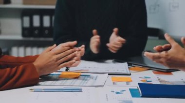 Projeyi grafik ve çizelge dokümanlarıyla bitirdikten sonra modern ofiste başarılı iş adamları alkışlıyor. 