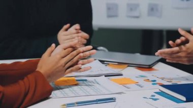 Projeyi grafik ve çizelge dokümanlarıyla bitirdikten sonra modern ofiste başarılı iş adamları alkışlıyor. 