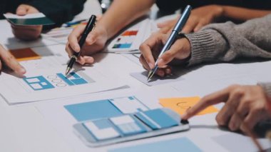Yeni mobil uygulama ve web sitesi için renkli UX modelleri ve prototipleriyle çalışan tasarımcı takımı