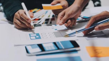 Yeni mobil uygulama ve web sitesi için renkli UX modelleri ve prototipleriyle çalışan tasarımcı takımı