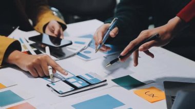 Yeni mobil uygulama ve web sitesi için renkli UX modelleri ve prototipleriyle çalışan tasarımcı takımı