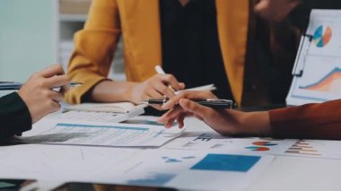 İş adamları modern ofisteki çizelgeleri ve grafikleri analiz eder.