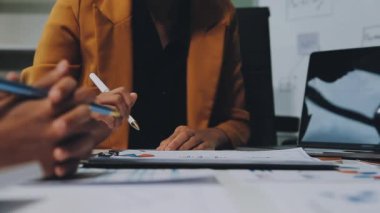 İş adamları modern ofisteki çizelgeleri ve grafikleri analiz eder.