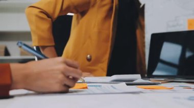 İş adamları modern ofisteki çizelgeleri ve grafikleri analiz eder.