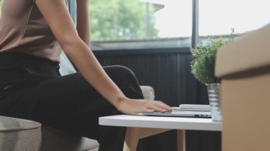 Genç Asyalı kadın oturma odasında dizüstü bilgisayar kullanıyor.