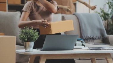 Dizüstü bilgisayarda çalışan ve evde akıllı telefon kullanan bir kadın.