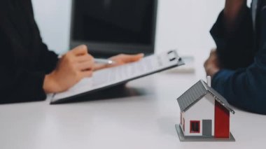 Sözleşmeyi imzalayan genç bir çift temsilci ya da temsilci ya da satın alma ya da borç alma ya da sigorta ya da mülk satın alma, gerçek ev satın alma ve