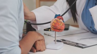 Üniformalı genç Asyalı erkek doktor kalp atışı yapıyor..