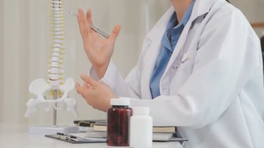 Beyaz üniformalı doktor steteskop tutuyor ve kameraya bakıyor.