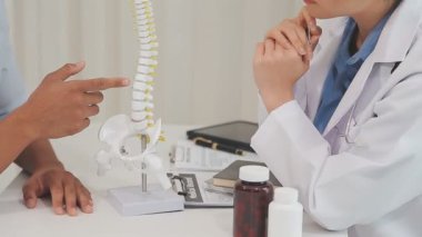 Doktor muayenehanede omurga modelini inceliyor.