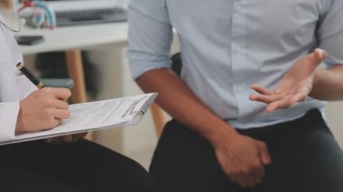 Doktor ve hasta hastane masasında oturuyor.