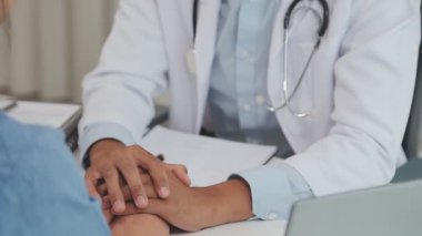 Bir hastanın elini tutan doktorun ellerini yakın çekim..