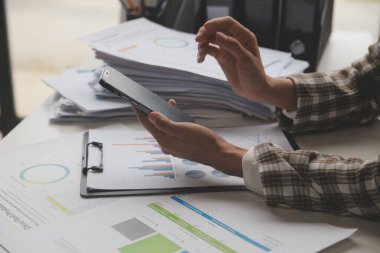 Group of confident business people point to graphs and charts to analyze market data, balance sheet, account, net profit to plan new sales strategies to increase production capacity.