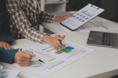 Group of confident business people point to graphs and charts to analyze market data, balance sheet, account, net profit to plan new sales strategies to increase production capacity.