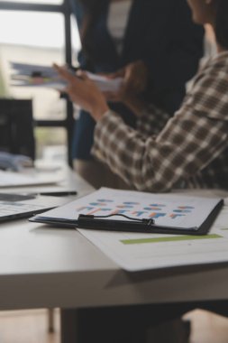 Group of confident business people point to graphs and charts to analyze market data, balance sheet, account, net profit to plan new sales strategies to increase production capacity.