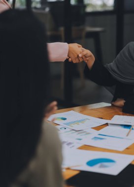 İş kadını ortaklığı el sıkışma konsepti. İki genç Asyalı iş adamı bir ofiste takım çalışmasını kutluyorlar..