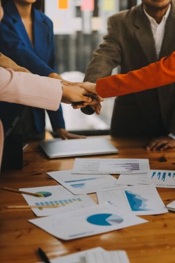 Bir grup iş adamı mutlu ve kendinden emin gülümsüyor. Birlikte çalışırken gülümseyerek ofiste el sıkışırken.