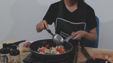 Asyalı kadın mutfakta yemek pişiriyor.