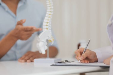 Ortopedistler dijital tablet tutuyor ve mankeni işaret ediyorlar. Osteoporoz, sırt ağrısı, bel, kiropraktik ve sağlık kavramı.