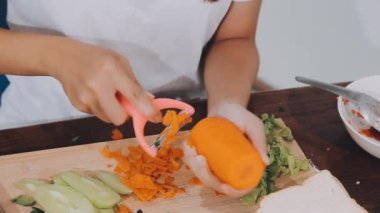 Tahta tahtada bıçakla taze havuç kesen bir kadın.