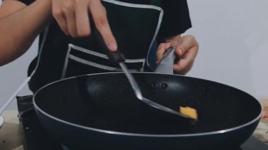 Genç bir kadın mutfakta yemek pişiriyor.