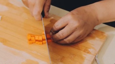 Tahtadaki bıçakla havucu kesiyor.