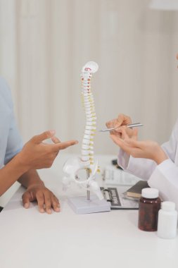 Ortopedistler dijital tablet tutuyor ve mankeni işaret ediyorlar. Osteoporoz, sırt ağrısı, bel, kiropraktik ve sağlık kavramı.