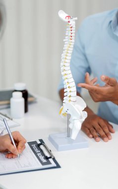 Ortopedistler dijital tablet tutuyor ve mankeni işaret ediyorlar. Osteoporoz, sırt ağrısı, bel, kiropraktik ve sağlık kavramı.