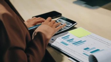 Ofiste belgeler ve belgeler üzerinde çalışırken dijital tablet kullanan genç iş kadını